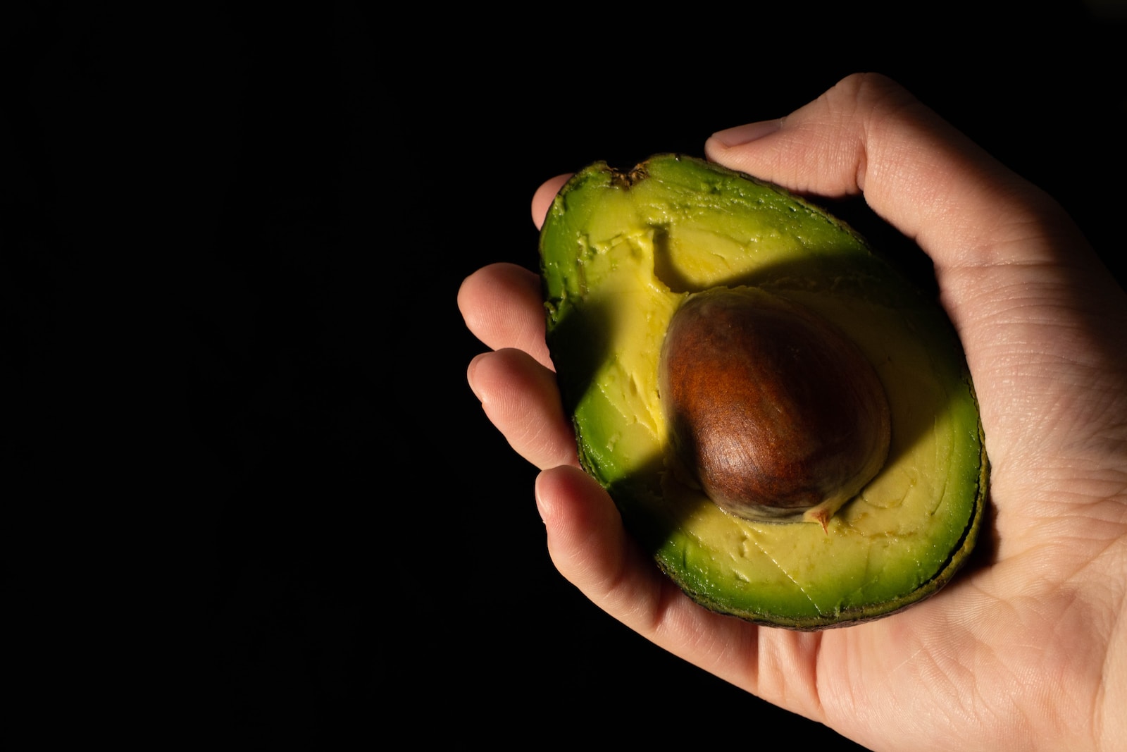 a person holding an avocado in their hand